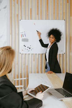 Confident businesswoman leading a presentation using a whiteboard in a modern office.